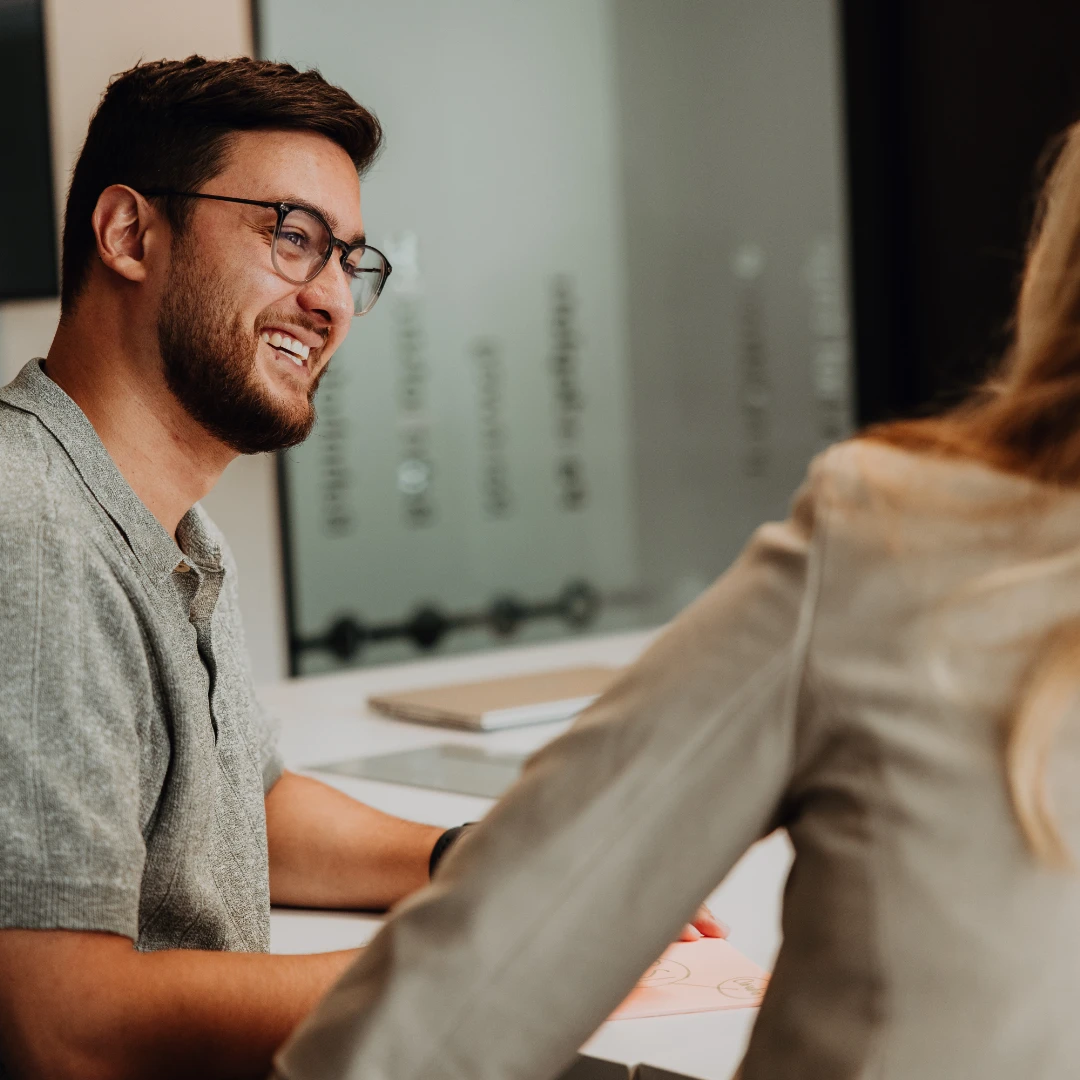 Two employees in conversation at a table, smiling and exchanging ideas—open communication, personal growth, and a supportive environment for a successful career start at BSI Software.