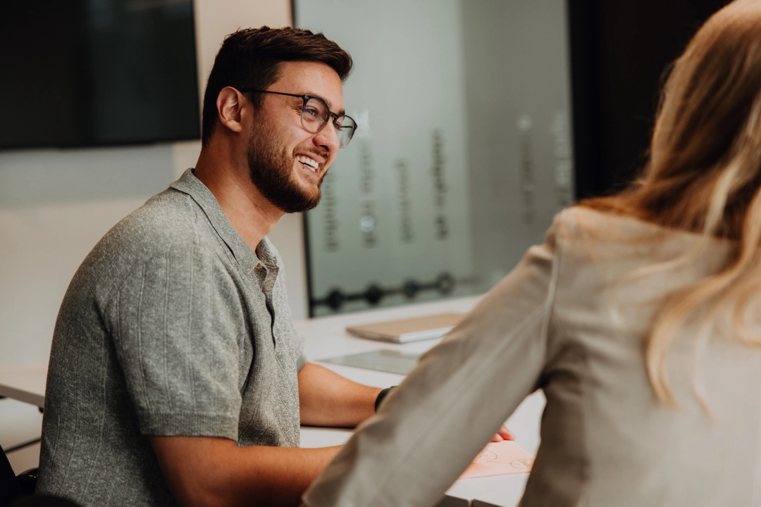 Two employees in conversation at a table, smiling and exchanging ideas—open communication, personal growth, and a supportive environment for a successful career start at BSI Software.