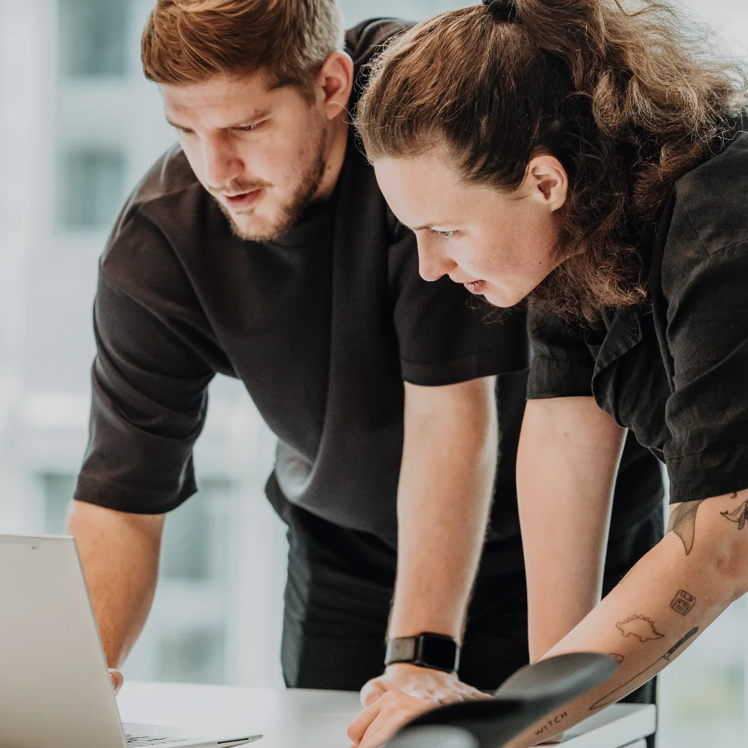 Zwei Mitarbeitende arbeiten eng zusammen am Laptop und analysieren Inhalte – kollaboratives Arbeiten, Wissensaustausch und praxisnahes Lernen für Lernende bei BSI Software.