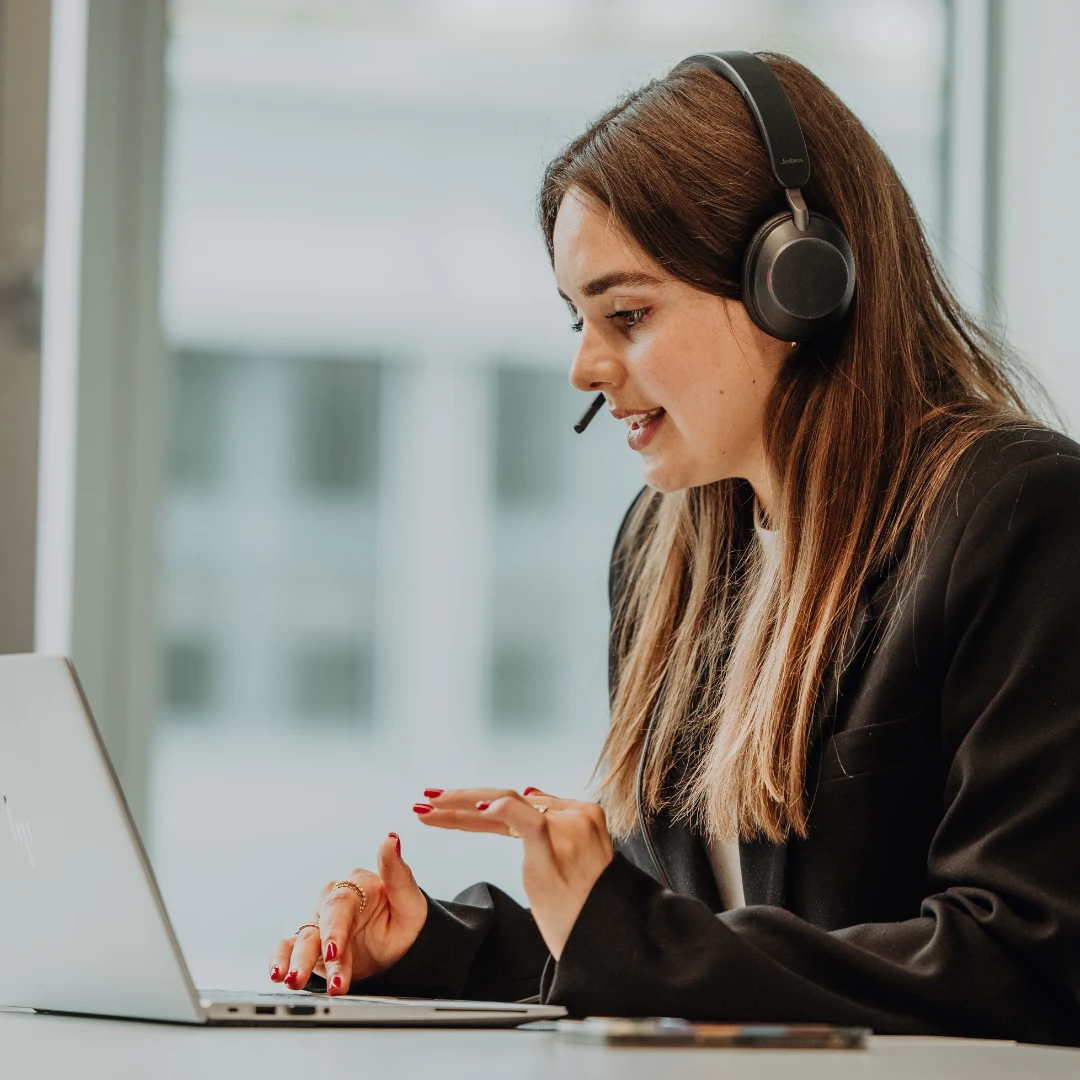 Mitarbeitende im Praktikum oder Werkstudium arbeitet mit Headset am Laptop und nimmt an einem virtuellen Austausch teil – flexible Arbeitsmodelle, persönliche Entwicklung und praxisnahe Einblicke bei BSI Software.