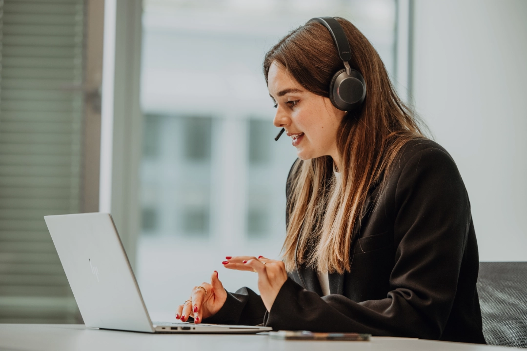 An intern or working student uses a laptop with a headset, participating in a virtual exchange—flexible work models, personal growth, and hands-on experience at BSI Software.