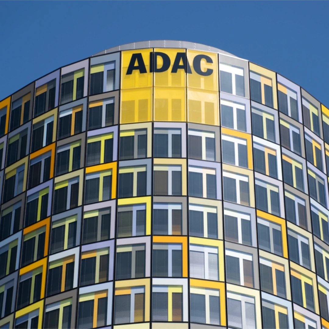 ADAC headquarters with a modern yellow and grey glass facade symbolizing Germany’s largest data migration to the BSI Customer Suite. The image represents digital transformation, customer relationship management, and future-oriented IT infrastructure.