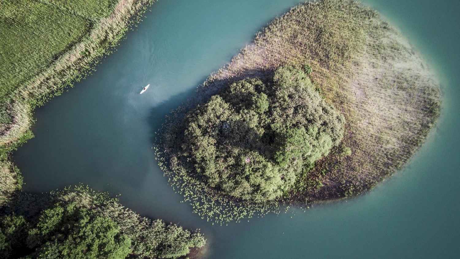 Aerial view of a kayak on a turquoise river surrounded by lush riverside vegetation – symbolizing sustainability, connection to nature, and BSI Software's commitment to environmental and social responsibility.